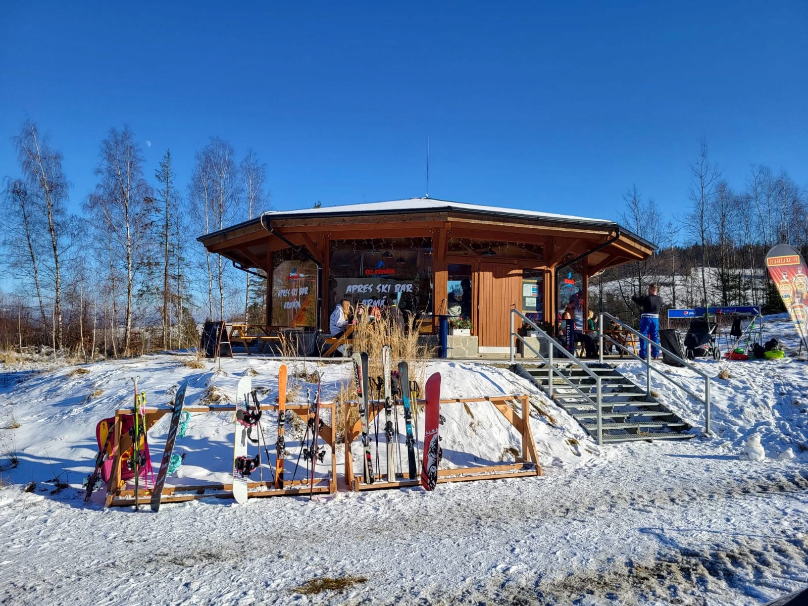 Apres Ski Bar Armáda – dřevěný bar v areálu za slunečného zimního dne